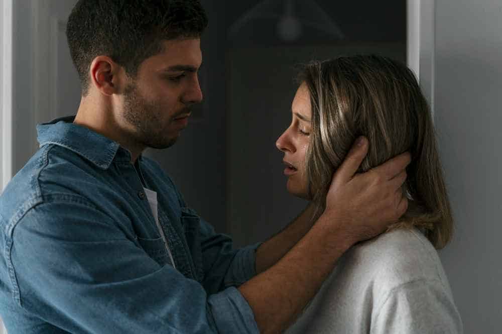 Pareja en un momento tenso, él consuela a ella que muestra dolor emocional
